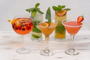 Selezione di cocktail colorati con guarnizioni di frutta fresca e menta