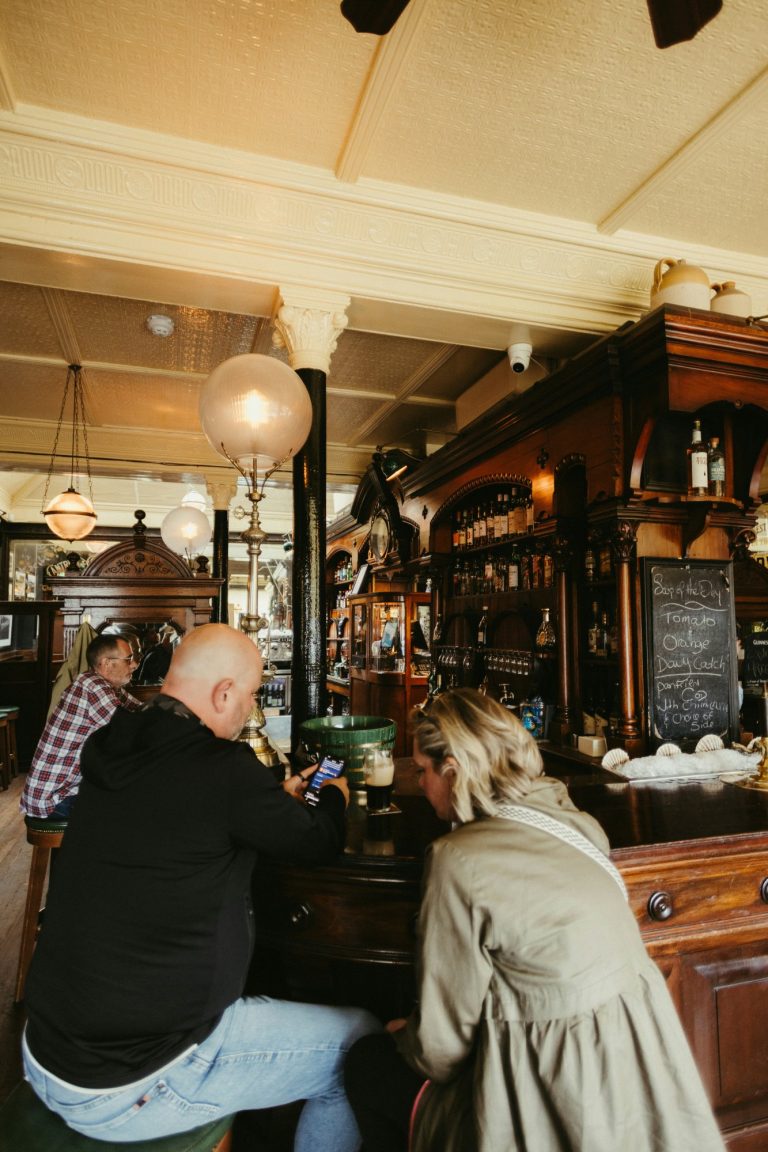 Bancone in legno del pub con sgabelli e bottiglie sullo sfondo