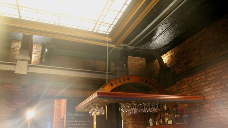 Interno con parete in mattoni a vista e bicchieri appesi al soffitto